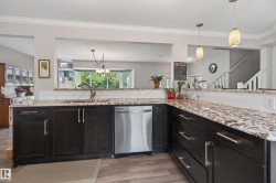 Kitchen featuring dark wood cabinetry, light-toned granite countertops, and a subway tile backsplash - 