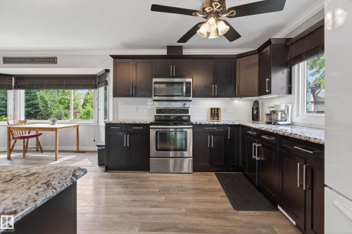 Kitchen featuring dark wood cabinetry, light-toned wood-finish flooring, and white subway tile backsplash - 10 Abbey Crescent, St. Albert, AB - Indoor Photo Showing Kitchen With Upgraded Kitchen
