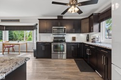 Kitchen featuring dark wood cabinetry, light-toned wood-finish flooring, and white subway tile backsplash - 