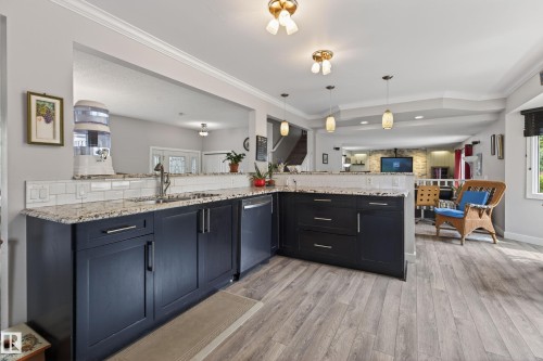 Open-concept kitchen featuring dark cabinetry, speckled countertops, and a white subway tile backsplash - 10 Abbey Crescent, St. Albert, AB - Indoor Photo Showing Kitchen