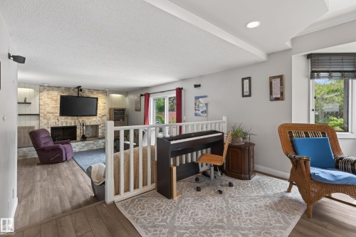 Lower level living space featuring a light-toned brick fireplace with hearth, recessed lighting, wood-finish flooring, and a sliding glass door leading to the exterior - 10 Abbey Crescent, St. Albert, AB - Indoor