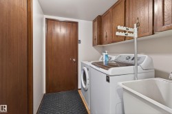 Dedicated laundry area featuring wood-finish flooring, a utility sink, and wall-mounted cabinetry - 
