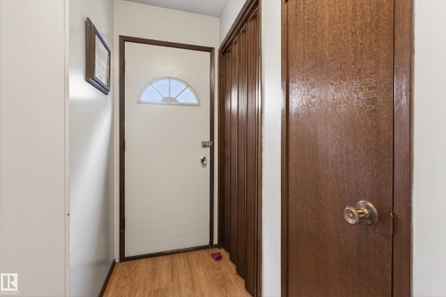 Entryway featuring a white door with an arched window, wood-finish flooring, and a solid wood-panel interior door - 10 Abbey Crescent, St. Albert, AB - Indoor Photo Showing Other Room