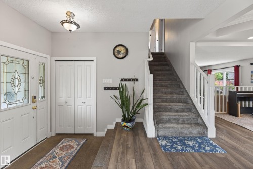 Inviting entryway featuring wood-finish flooring, a white front door with decorative glass inserts, and a bi-fold closet - 10 Abbey Crescent, St. Albert, AB - Indoor Photo Showing Other Room