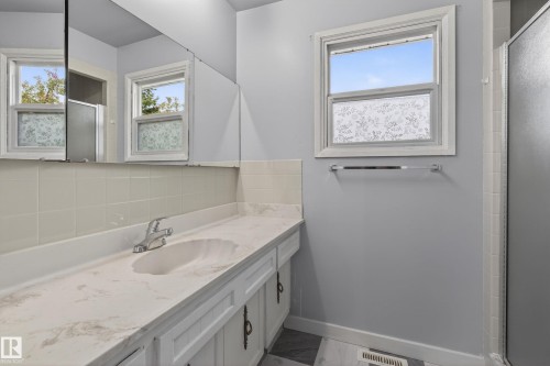 Contemporary bathroom featuring a white vanity with an integrated sink, a light-toned countertop, and white cabinetry - 10 Abbey Crescent, St. Albert, AB - Indoor Photo Showing Bathroom