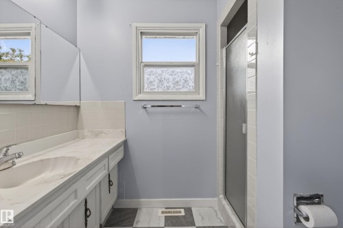 Bathroom featuring a white vanity with an integrated sink, patterned white countertop, white cabinet storage, and a chrome faucet - 10 Abbey Crescent, St. Albert, AB - Indoor Photo Showing Bathroom
