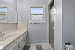Bathroom featuring a white vanity with an integrated sink, patterned white countertop, white cabinet storage, and a chrome faucet - 