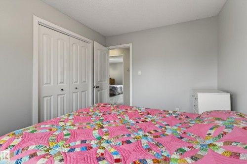 Bedroom featuring light grey wall paint, bi-fold closet doors with black hardware, and a white dresser - 10 Abbey Crescent, St. Albert, AB - Indoor Photo Showing Bedroom