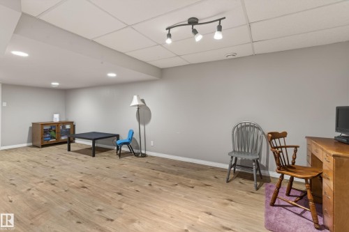 Spacious room featuring wood-finish flooring, light grey walls, and a white grid ceiling - 10 Abbey Crescent, St. Albert, AB - Indoor