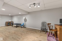 Spacious room featuring wood-finish flooring, light grey walls, and a white grid ceiling - 