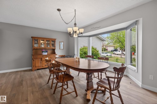 Bay window providing abundant natural light, wood-finish flooring, neutral gray wall paint, and a classic chandelier - 10 Abbey Crescent, St. Albert, AB - Indoor Photo Showing Dining Room