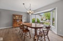 Bay window providing abundant natural light, wood-finish flooring, neutral gray wall paint, and a classic chandelier - 10 Abbey Crescent, St. Albert, AB  - Indoor Photo Showing Dining Room 