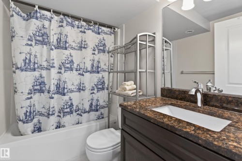 Bathroom featuring a tub/shower combination, dark wood-finish vanity, integrated rectangular sink, chrome faucet, and stone-finish countertop - 10 Abbey Crescent, St. Albert, AB - Indoor Photo Showing Bathroom