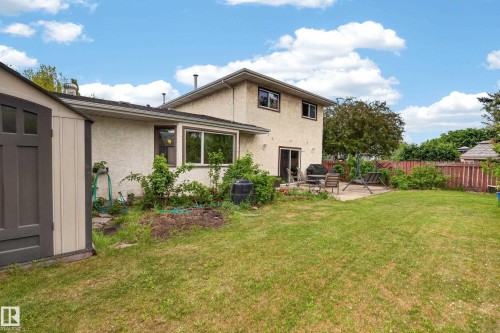 Expansive backyard featuring a manicured lawn, concrete patio, and mature perimeter trees - 10 Abbey Crescent, St. Albert, AB - Outdoor