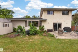 Rear exterior featuring stucco siding, multiple windows, and a sliding patio door - 