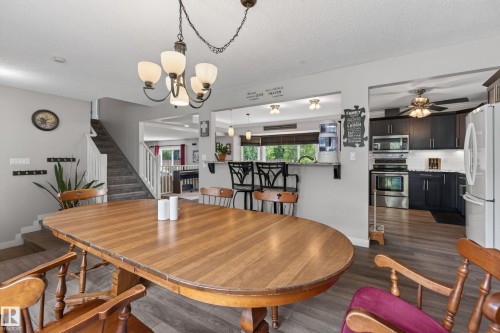 Open-concept dining area featuring wood-finish flooring, a contemporary chandelier, and a breakfast bar - 10 Abbey Crescent, St. Albert, AB - Indoor Photo Showing Dining Room