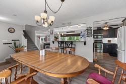 Open-concept dining area featuring wood-finish flooring, a contemporary chandelier, and a breakfast bar - 