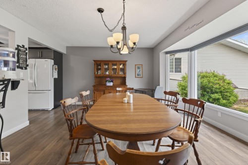 Dining area featuring wood-finish flooring, a contemporary chandelier, and a large bay window - 10 Abbey Crescent, St. Albert, AB - Indoor Photo Showing Dining Room