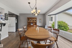 Dining area featuring wood-finish flooring, a contemporary chandelier, and a large bay window - 