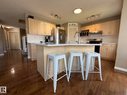 Kitchen with an island featuring a white countertop and seating for three - 1820 Robertson Crescent Sw, Edmonton, AB - Indoor Photo Showing Kitchen