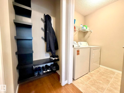 Dedicated laundry area featuring ceramic tile flooring, a mounted wire shelf, and light neutral walls - 1820 Robertson Crescent Sw, Edmonton, AB - Indoor Photo Showing Laundry Room
