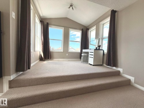 Carpeted loft space featuring a vaulted ceiling and multiple windows - 1820 Robertson Crescent Sw, Edmonton, AB - Indoor Photo Showing Other Room