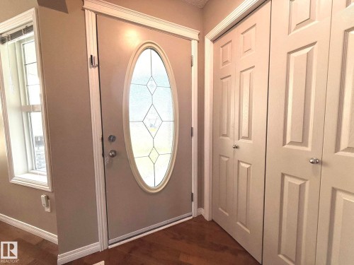 Entryway featuring a decorative oval-paneled door, sidelight window, and wood-finish flooring - 1820 Robertson Crescent Sw, Edmonton, AB - Indoor Photo Showing Other Room