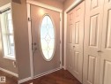 Entryway featuring a decorative oval-paneled door, sidelight window, and wood-finish flooring - 1820 Robertson Crescent Sw, Edmonton, AB  - Indoor Photo Showing Other Room 
