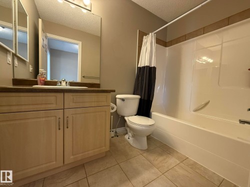 Bathroom featuring a vanity with light wood-finish cabinetry, a dark countertop, and an integrated sink with chrome fixtures - 1820 Robertson Crescent Sw, Edmonton, AB - Indoor Photo Showing Bathroom