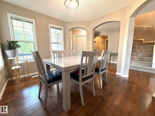 Spacious room featuring wood-finish flooring, multiple windows, and arched doorways - 1820 Robertson Crescent Sw, Edmonton, AB - Indoor Photo Showing Dining Room
