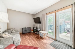 Living area featuring wood-finish flooring, light neutral wall paint, and double glass-paneled doors with exterior access - 