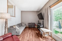 Living area featuring wood-finish flooring, a full-lite glass door, and white shiplap paneling - 
