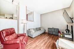 Open-concept room featuring wood-finish flooring, neutral wall tones, and a half-wall partition with vertical paneling - 