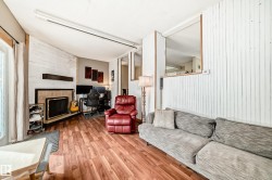 Living area featuring wood-finish flooring, a fireplace with a tile surround and dark mantel, and white shiplap accent walls - 