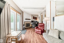Living area with wood-finish flooring, a corner fireplace with a tiled surround, and a natural wood mantle - 