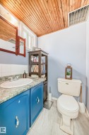 Bathroom featuring a wood-panel ceiling, light blue walls, and a window - 