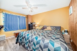Room featuring wood-finish flooring, a ceiling fan, and a wood-paneled accent wall - 
