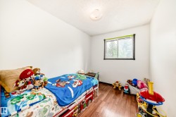 Bright room with wood-finish flooring, a light-colored ceiling, and a window with dark trim - 