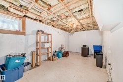 Unfinished lower level featuring exposed ceiling joists, concrete walls, a single window, and an exposed light fixture - 