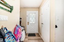 Entryway featuring a decorative glass-paneled door, wood-finish flooring, and light-toned walls - 