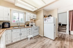 Kitchen featuring white cabinetry, light wood-finish countertops, and a double basin stainless steel sink - 