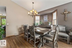Dining area featuring wood-finish flooring, a tiered chandelier, and a bay window with blinds - 