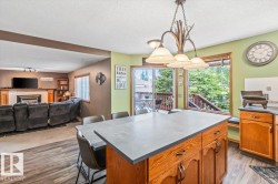 Kitchen island with grey countertop, wood cabinetry, and pendant lighting - 