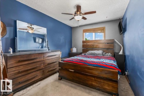 Spacious bedroom featuring contrasting wall colors, a ceiling fan with integrated lighting, and a window with wood-finish trim - 16 Harrold Place, St. Albert, AB - Indoor Photo Showing Bedroom