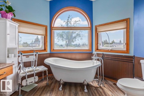 Clawfoot tub with chrome fixtures, wood-finish flooring, and a large arched window - 16 Harrold Place, St. Albert, AB - Indoor Photo Showing Bathroom