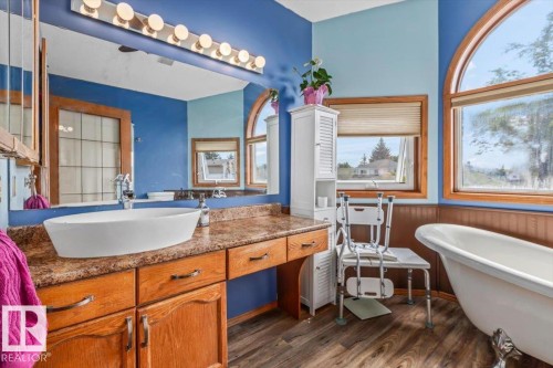 Bathroom featuring a freestanding clawfoot tub, wood-finish flooring, and a vanity with a vessel sink - 16 Harrold Place, St. Albert, AB - Indoor Photo Showing Bathroom