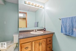 Bathroom vanity with a built-in sink, dark speckled countertop, and light wood cabinetry - 