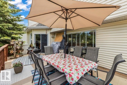 Spacious outdoor deck featuring light-colored siding, a brown wood railing, and a large sliding glass door - 16 Harrold Place, St. Albert, AB - Outdoor With Deck Patio Veranda With Exterior