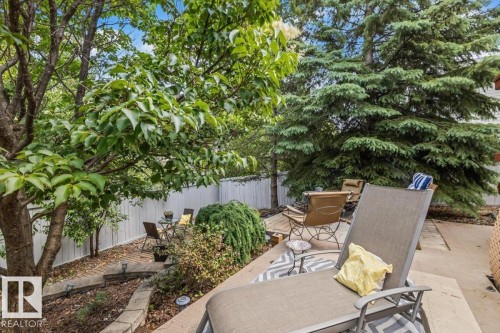 Private outdoor space featuring a stone patio, a multi-level garden bed with retaining walls, and mature trees providing natural screening - 16 Harrold Place, St. Albert, AB - Outdoor