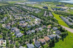 Aerial perspective showcasing a residential area with mature trees, green spaces, and a lake in the distance - 